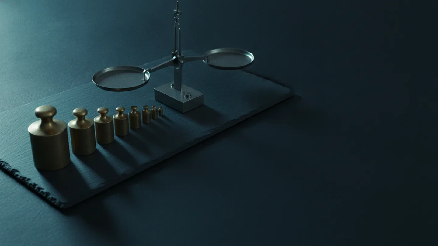 A set of graduated brass weights beside an idle steel balance scale on dark slate, lit cold with a cyan edge